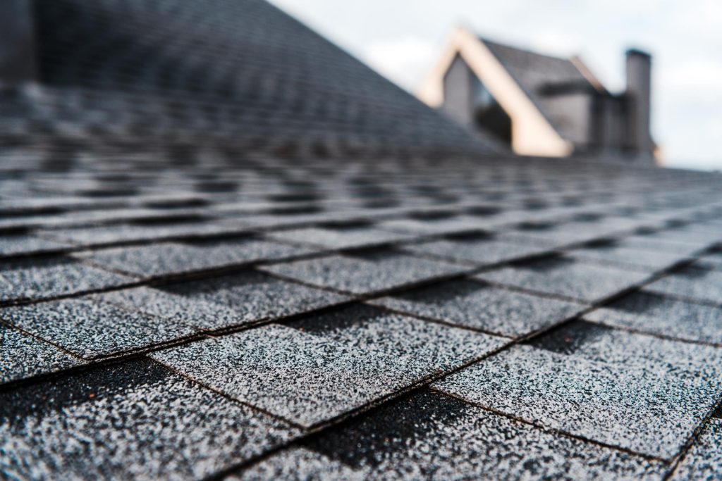 Roof repair technician inspecting roof shingles in Miami