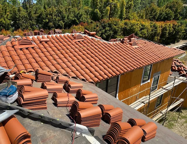 Roof under construction with stacks of terracotta tiles on the roof and scaffolding along the side
