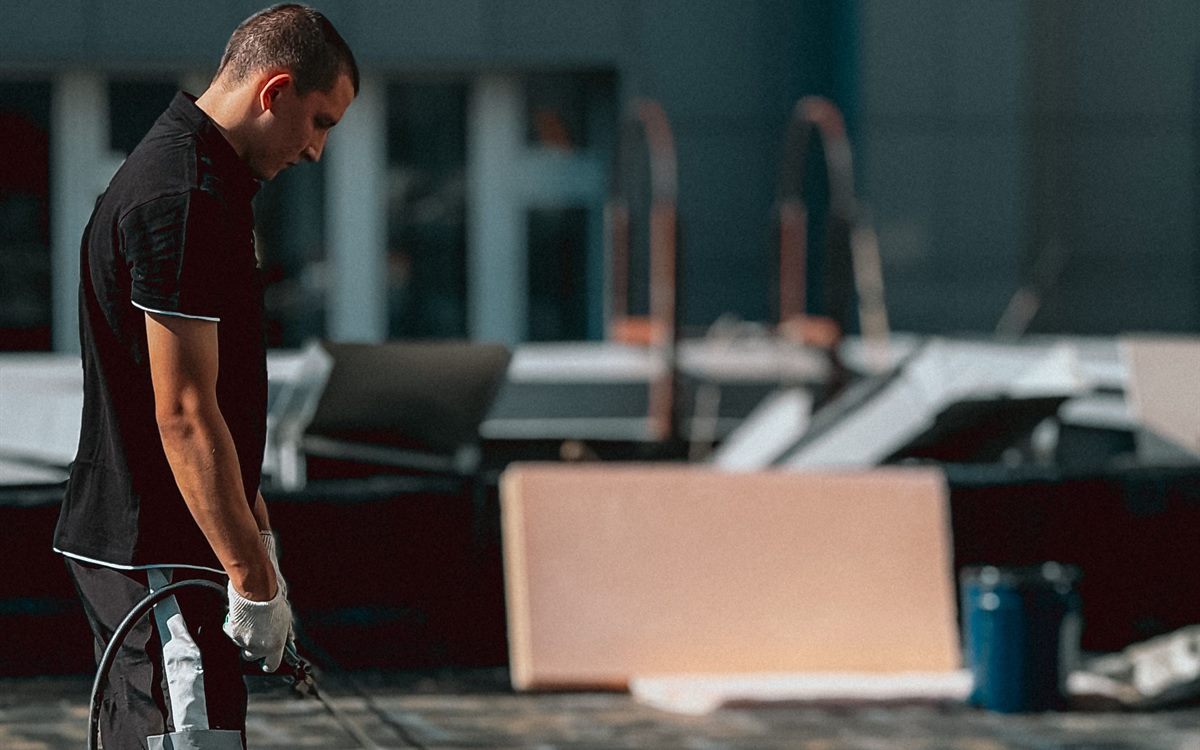 Roofing technician working with a torch on a commercial building rooftop