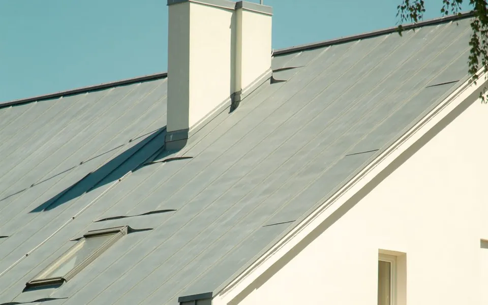 Standing seam metal roof with raised seams, chimney flashing and a skylight