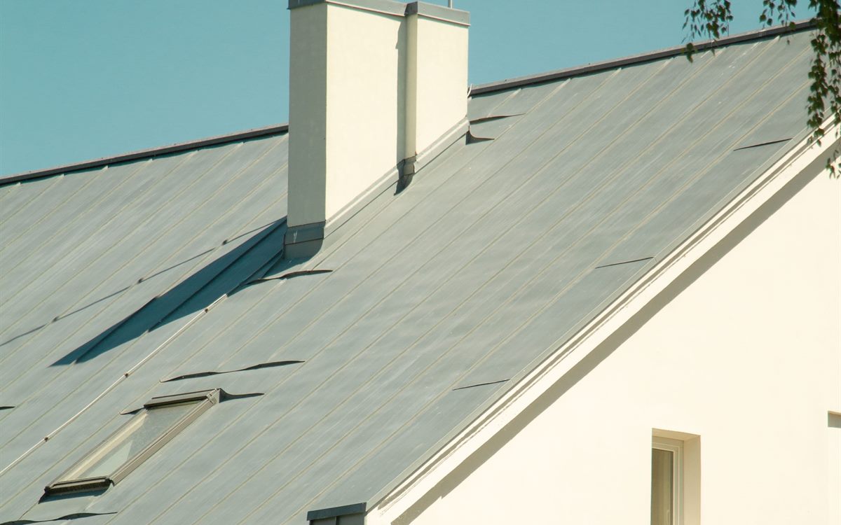 Standing seam metal roof with raised seams, chimney flashing and a skylight