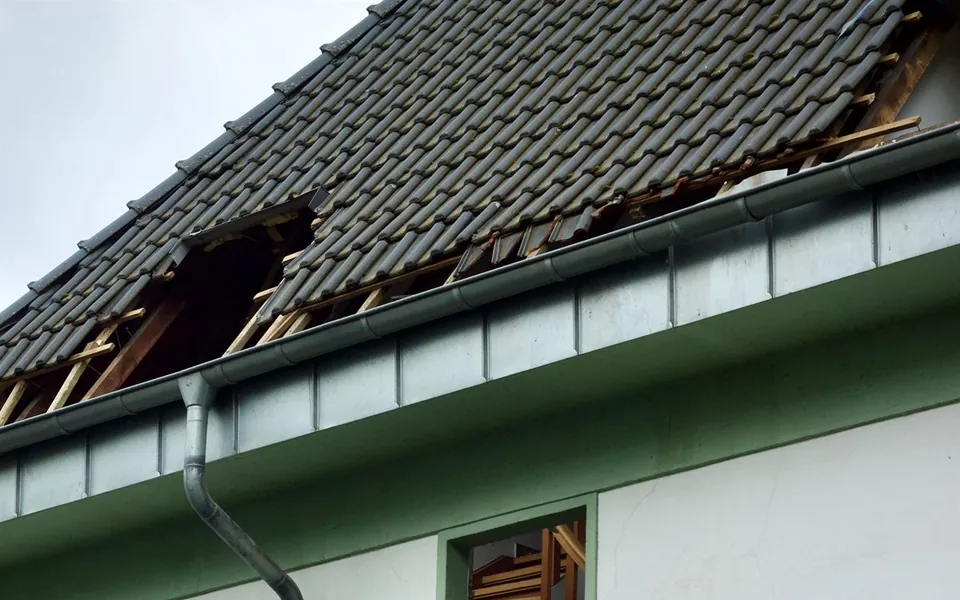 Storm damaged roof with tiles torn away and roof battens left exposed