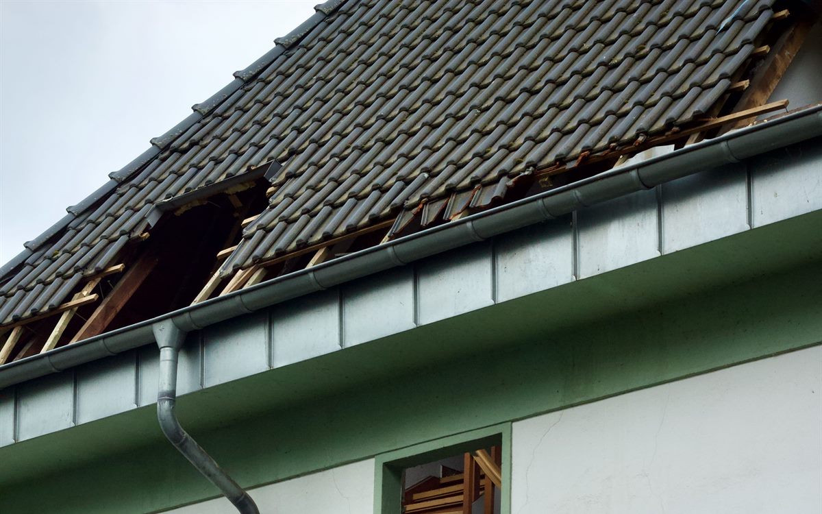 Storm damaged roof with tiles torn away and battens left exposed