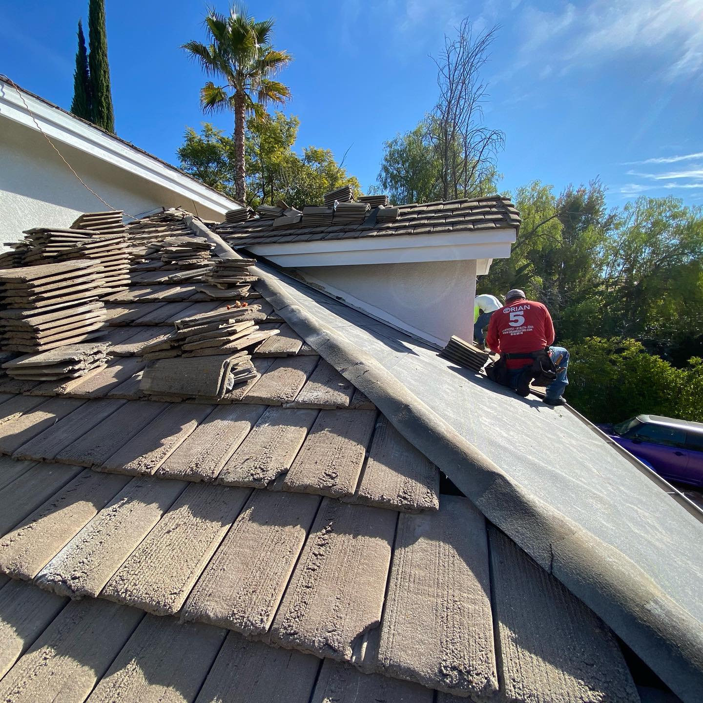 Roofers replacing damaged roof shingles on a house